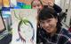 邱曉詩與學生合影，手上拿的是她的自畫像